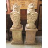 A pair of weathered stoneware lions holding shields on plinths