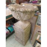 A composite stone garden urn with leaf design bowl on pedestal