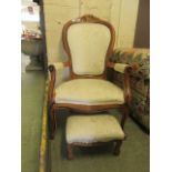 A reproduction open armchair along with matching stool upholstered in a white gold floral fabric