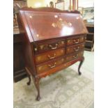 An eastern hardwood bureau having an inlaid brass design with pull-down flap and assortment of four