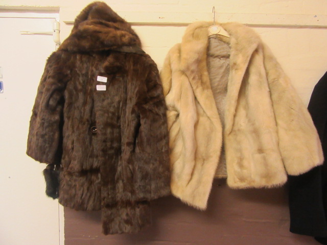 A brown fur coat and scarf along with a white fur jacket