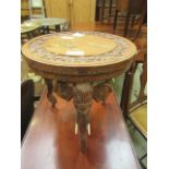 An eastern carved occasional table supported on three carved elephant design supports