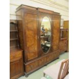 An Edwardian burr walnut triple door wardrobe having oval bevelled glass mirror over two drawers