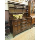 A dark Ercol dresser having a raised plate rack to back and four drawers flanked by cupboard doors