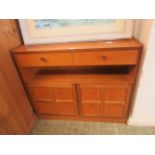 A mid-20th century teak cabinet having a large drawer above open storage above two panel doors