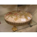 An early Victorian gilt wood circular foot stool having a needlework to top and lions paw feet