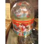 A mid-20th century tin with a model of a fun fair carousel in the dome topped lid