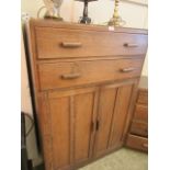 A mid-20th century tall boy having two drawers above two cupboard doors together with a matching