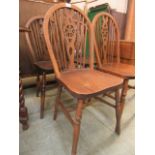 A set of four wheel back dining chairs