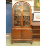 A mid-20th century dome topped oak display cabinet having a pair of doors below