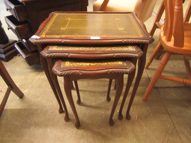 A nest of three mahogany effect and tooled leather topped tables