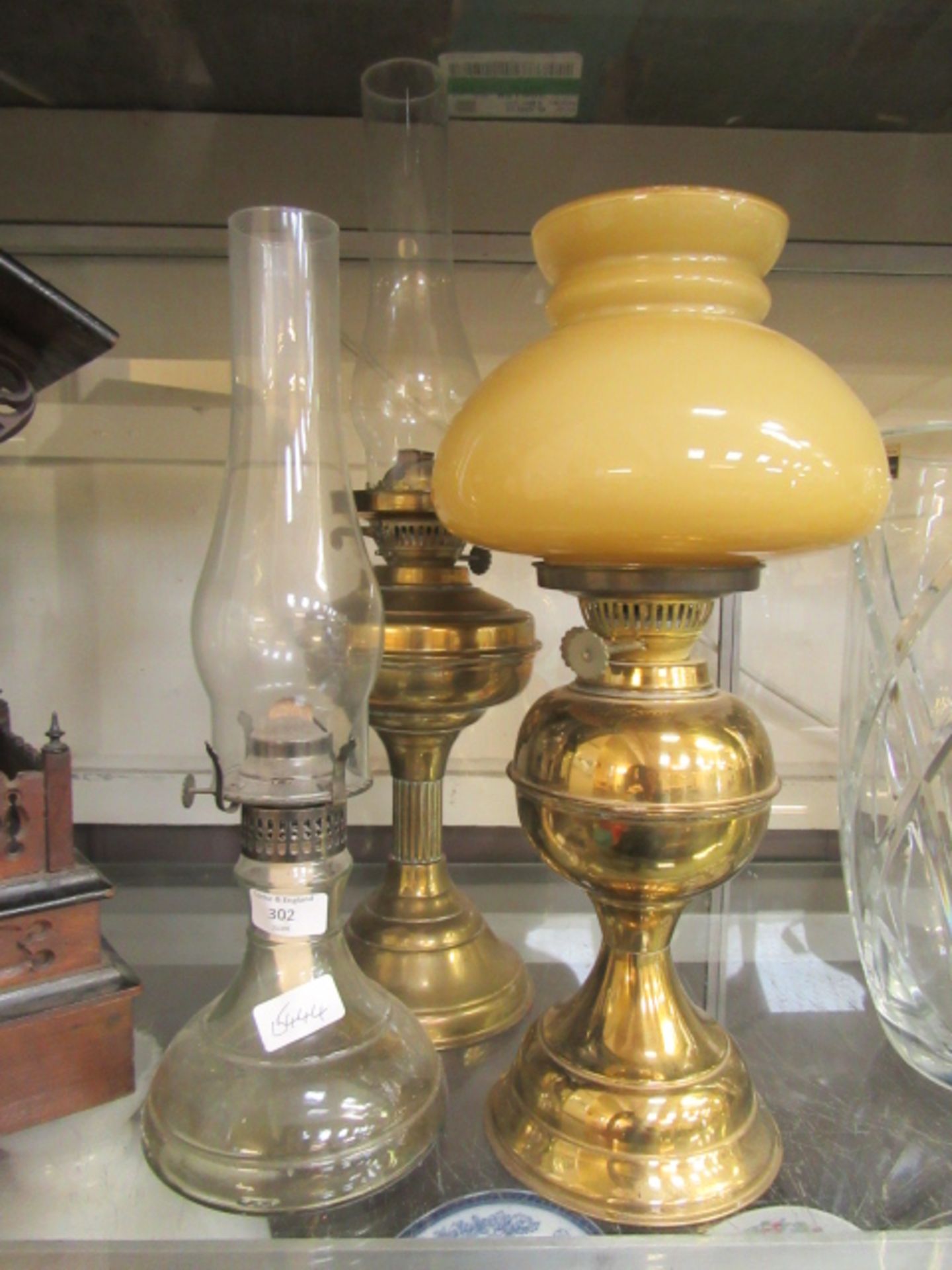 Two brass oil lamps along with a glass oil lamp