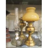 Two brass oil lamps along with a glass oil lamp