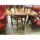 A mid-20th century oak gate leg table with barley twist supports