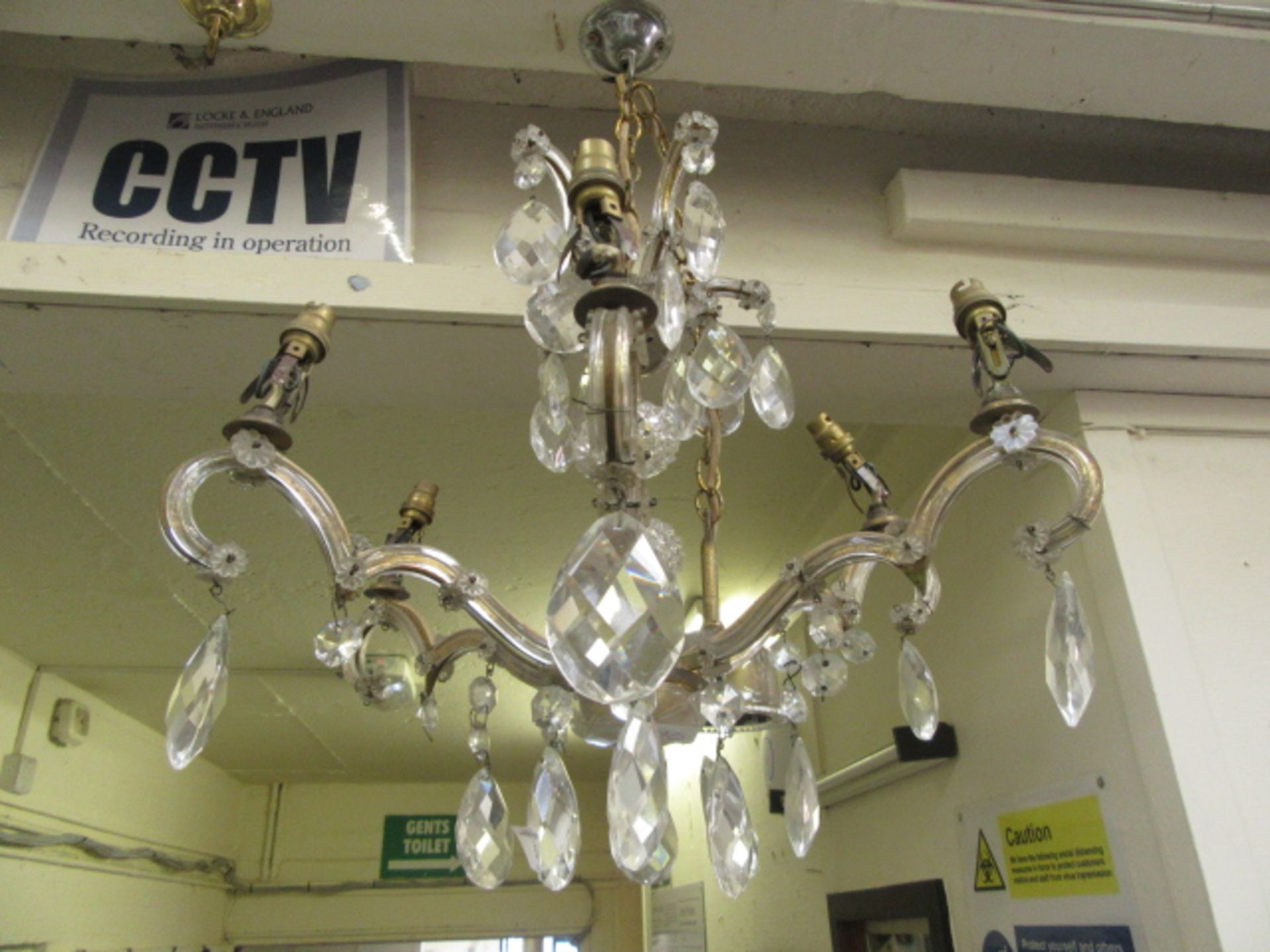 An early 20th century six branch brass and cut glass ceiling hanging chandelier