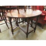 A mid-20th century oak drop leaf table with barley twist supports