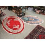 An oval red Chinese rug together with an oval blue Chinese rug