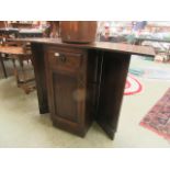 A mid-20th century oak bar having single drawer and cupboard door with drop leaves and the reverse