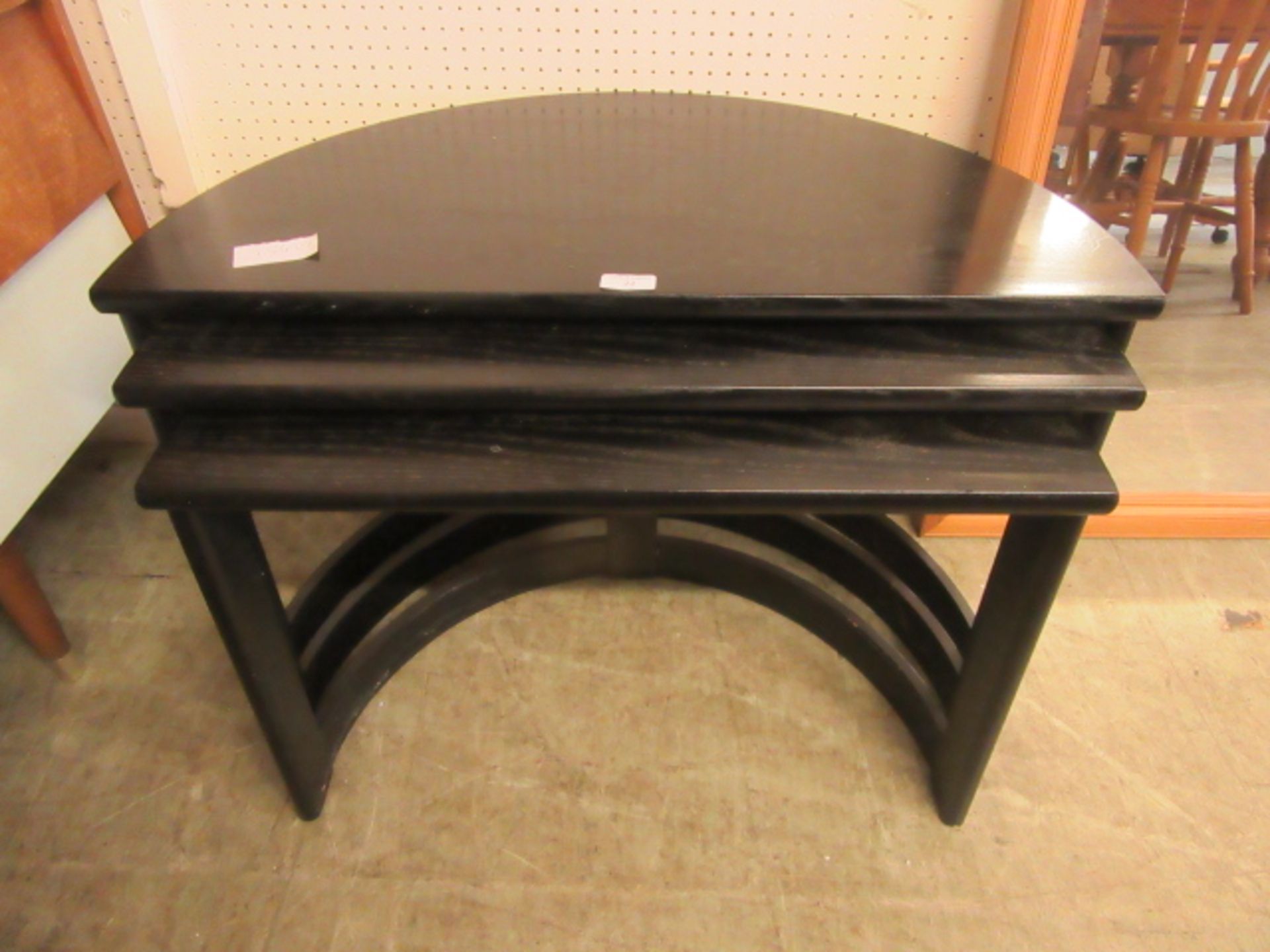 A nest of three black ash demi-lune tables