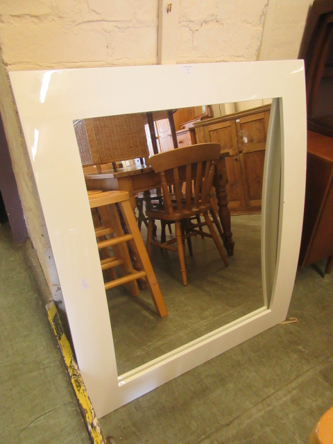 A modern white framed bow fronted mirror