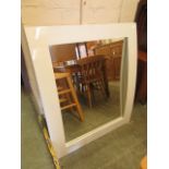 A modern white framed bow fronted mirror