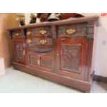 An Edwardian walnut break front sideboard having an assortment of carved drawer fronts and doors