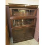 A mid-20th century oak bookcase having three tiers with two glazed top sections with panel doors to