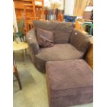 A large brown upholstered swivel chair with matching stool