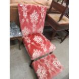 A pink floral upholstered nursing chair with matching stool