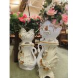 Two white ceramic gold painted jardiniere stands with swan design together with artificial flowers