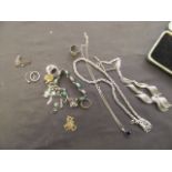 A box containing an assortment of white metal chains, green beads, brooches,