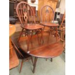 A dark Ercol drop leaf table with a set of four matching wheel back chairs