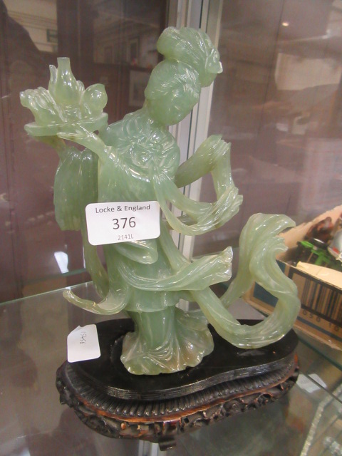 A jade style carved eastern style figure on stand