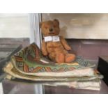 A small loved teddy bear together with an assortment of fabric,