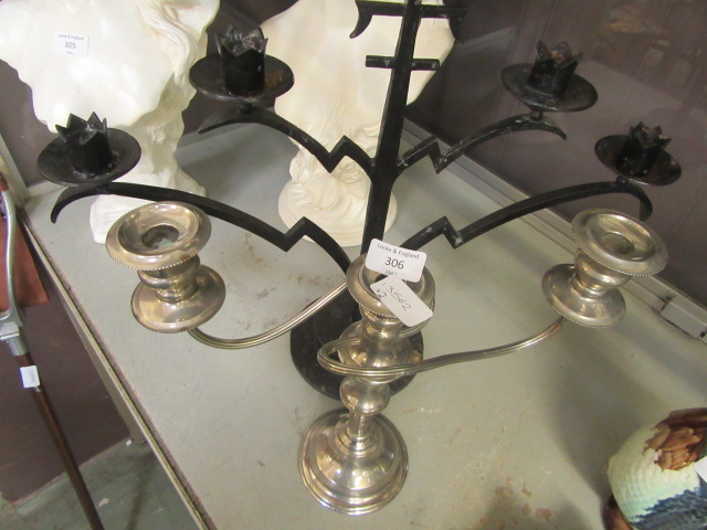 A black metal work candelabra together with a plated candelabra