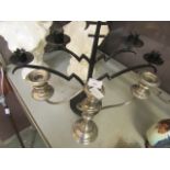 A black metal work candelabra together with a plated candelabra