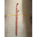 A walking cane with a brass duck handle together with a large wooden hiking stick