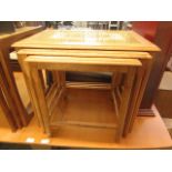 A nest of three teak occasional tables with tiled tops