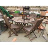 A weathered teak folding garden table along with a set of four folding chairs