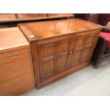 A light Ercol cabinet having lift up lid with two cupboard doors