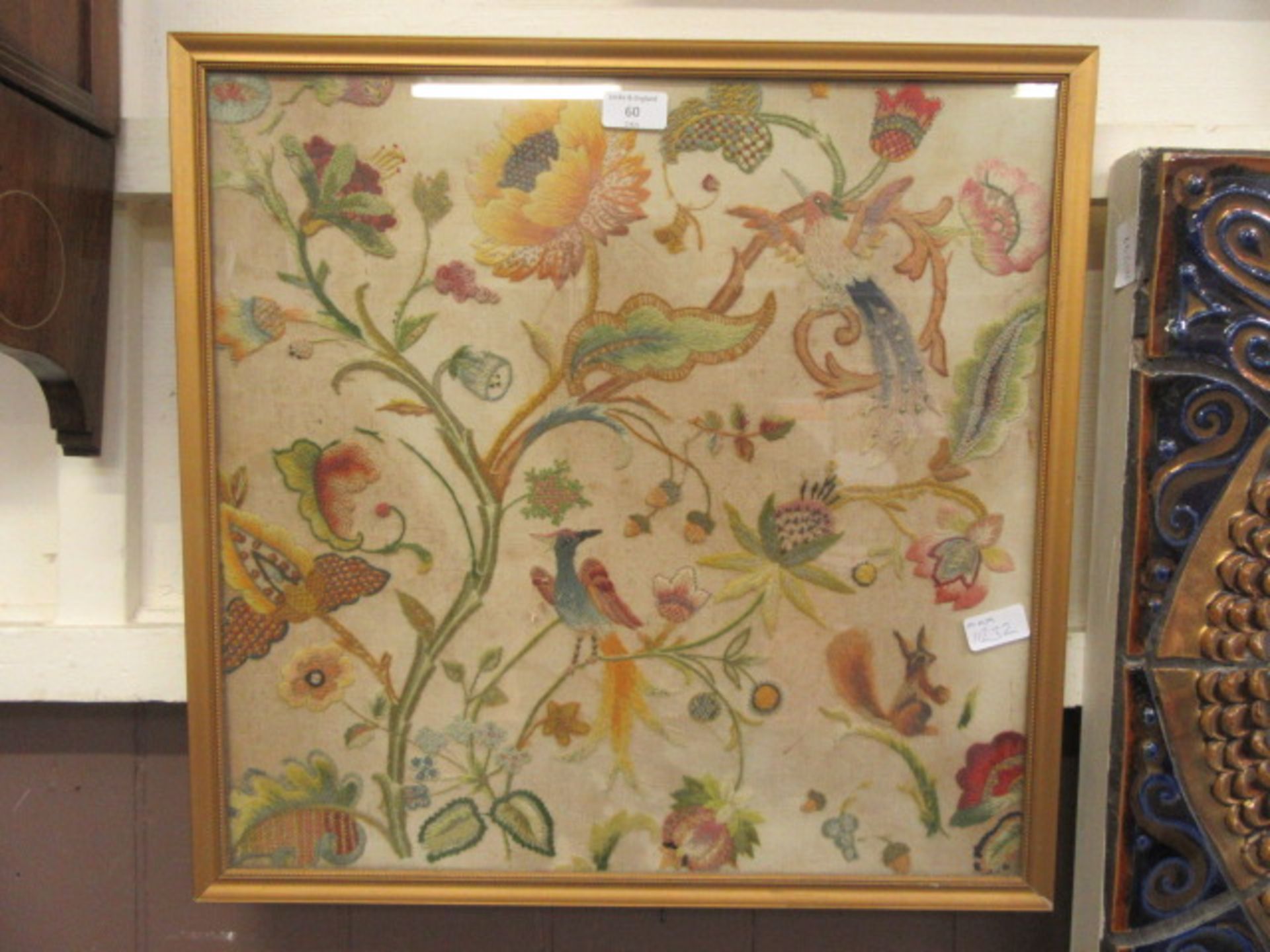 A framed and glazed possible 18th century crewel work panel depicting birds, flowers,