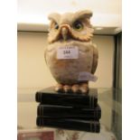 An alabaster carved figure of owl sat on simulated books