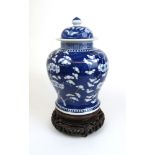 A 19th century Chinese blue and white prunus vase of baluster form having a lid and hardwood stand.