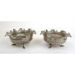 A pair of eastern white metal footed bowls with fluted rims and embossed and chased naturalistic