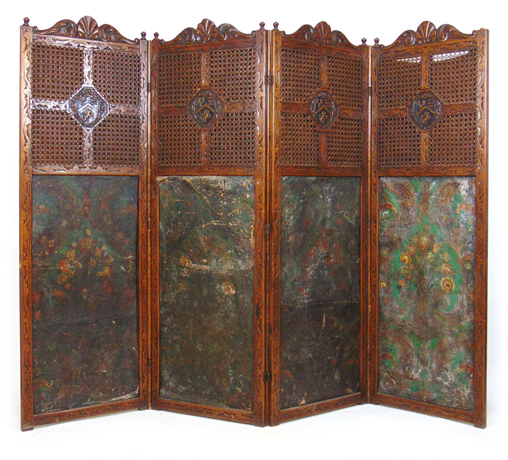 A 19th century carved oak four fold screen with cane surrounding a carved armorial crest over