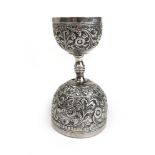 An Indian white metal double measure embossed with floral decoration. Approx weight 78g. h.