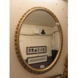 An ornate oval gilt framed mirror