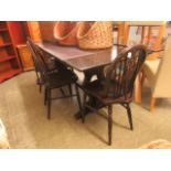 A dark oak extending dining table along with a set of four wheel back chairs