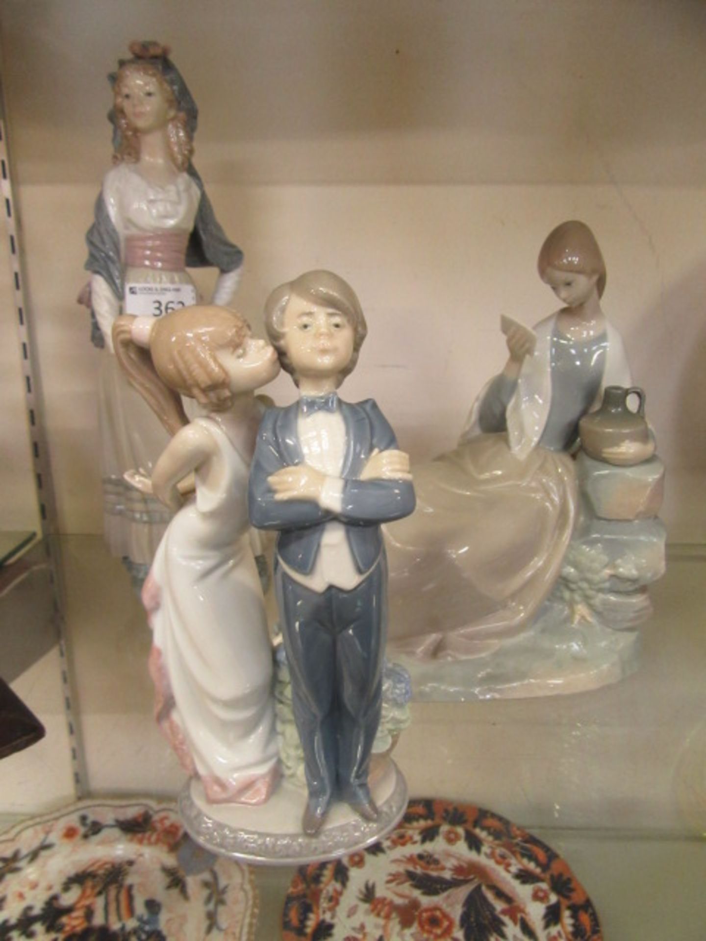 Two Lladro figurines and one Wade figurine, one of page boy and girl, another of tall elegant lady,