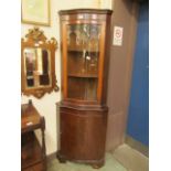 A reproduction mahogany serpentine fronted floor standing corner cupboard